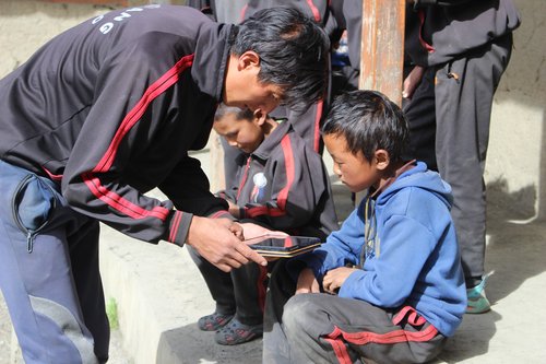A teacher at Sidhhartha Kula Basic School, Tinje, Dolpo assisting his students with E-Paath and other resources on tablets provided by OLE Nepal.